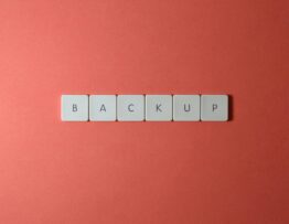 Free Close-up of keyboard keys spelling 'BACKUP' placed on a coral-colored surface. Stock Photo