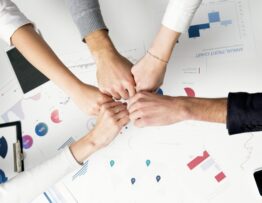 Free Colleagues celebrate success with a fist bump over financial charts depicting teamwork and unity. Stock Photo