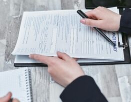 Free Close-up of hands analyzing insurance policy paperwork with pen on table. Stock Photo