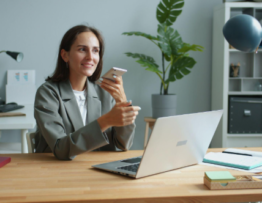 lady holding phone while working on a laptop